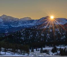 the sun shines brightly in front of snowy mountains