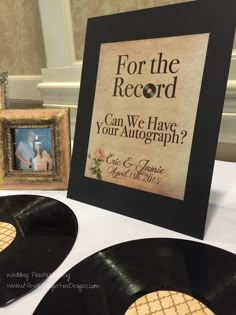 an old record is on the table next to two framed records and a sign that says, for the record can we have your autograph?