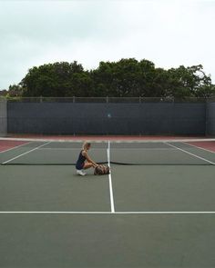 a man sitting on the tennis court with his racquet in front of him