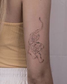 a woman's arm with a tiger tattoo on the left side of her arm