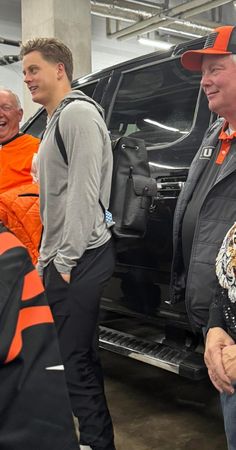 three men standing next to each other in front of a vehicle