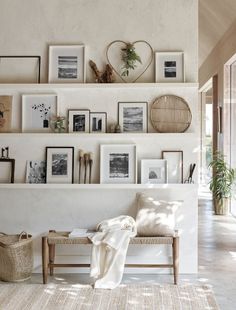 a living room with white walls and pictures on the wall, including a bench in front of