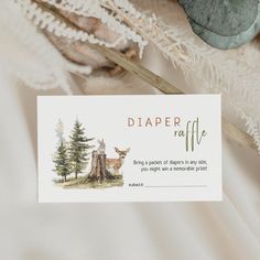 a card with a deer in the woods on it next to some feathers and trees