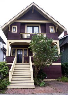 a purple house with stairs leading up to the front door and trees on either side