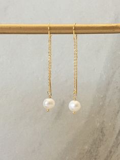 Simple, elegant and edgy design features an 8mm genuine freshwater pearl dangling from a long gold finished thread earring chain. Make a statement with these delicate and simple pearl thread earrings. Makes the perfect bridesmaid gift, wedding jewelry, Mother's Day or anniversary gift. Pearl(Genuine Freshwater) each pearl is slightly unique and naturally different 8mm Gold Earring Hoops 50mm (length) MATERIAL Genuine Freshwater Pearl 16K gold plated over high quality brass SKU:ER:123 To prolong Classic Bridal Earrings With Pearl Chain, Dangle Pearl Earrings For Bridesmaid Gift, Pearl Dangle Earrings For Bridesmaid Gift, Dangle Pearl Chain Earrings For Anniversary, Elegant Pearl Drop Threader Earrings For Formal Occasions, Delicate Pearl Chain Earrings For Formal Occasions, Delicate Pearl Chain Earrings For Formal Events, Delicate Formal Pearl Chain Earrings, Graceful Pearl Chain Earrings For Gifts