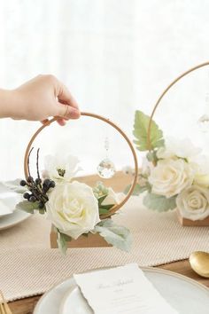 the table is set with white flowers and greenery in wooden hoop vases on top of each other