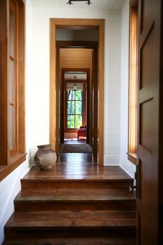 an empty hallway with wooden steps leading to another room