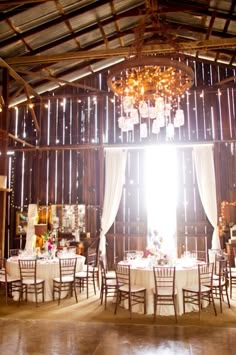 the inside of a barn with tables and chairs set up for a formal dinner or function