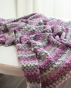 a crocheted blanket sitting on top of a white table next to a window