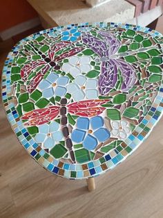 a colorful mosaic table top sitting on the floor