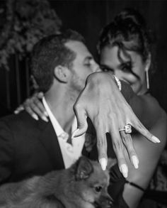 a man and woman with their hands touching each other's foreheads while the dog looks on