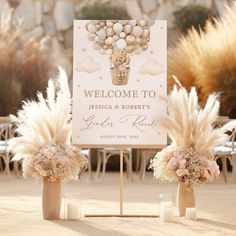 two vases filled with flowers next to a welcome sign