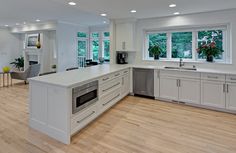 a large kitchen with white cabinets and wood floors