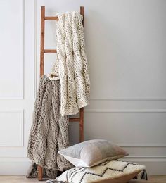 two pillows and a blanket are on the floor next to a ladder that is leaning against a wall