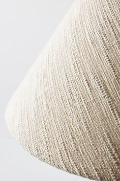 a close up view of a beige pillow on a white surface with the fabric pulled back