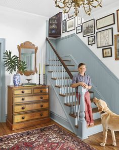 a boy and his dog are standing at the bottom of stairs in front of a staircase