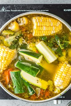 a pot filled with soup and corn on the cob