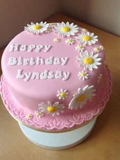 a pink birthday cake with daisies on it