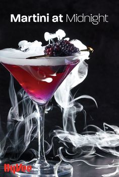 the martini at midnight is garnished with berries and ice cubes, on a black background