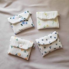 four small purses sitting on top of a bed next to each other with buttons in them