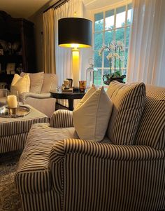 a living room filled with furniture and a lamp on top of a table in front of a window