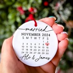 a hand holding a white ornament with a date printed on it