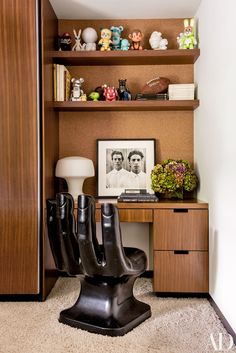 a desk with two chairs in front of it and shelves on the wall behind it