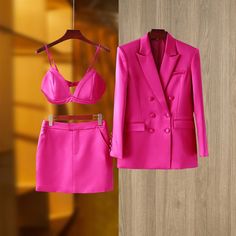 a bright pink suit and bra is hanging on a wooden wall next to a hanger