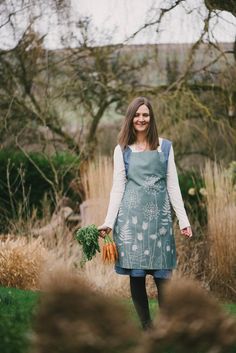 a woman standing in the grass holding carrots