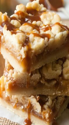 three dessert bars stacked on top of each other with caramel sauce drizzled over them