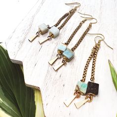 This pair of brass and Amazonite gemstone dangle earrings, features an 8mm Amazonite gemstone cube capped by two brass circles. It hangs from a 1.5" length of, golden brass, vintage, box chain and accented at the tip with a 6mm solid brass ball. Brass fish hook ear wires. Nickel free.Items will ship on our in-house, hand branded, leather earring cards. Earring Cards, Vintage Box, Brass Chain, Box Chain, Fish Hook, Free Items, Leather Earrings, Ear Wires, Gemstone Earrings