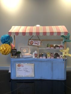 an ice cream stand is set up with paper flowers and decorations on the top shelf