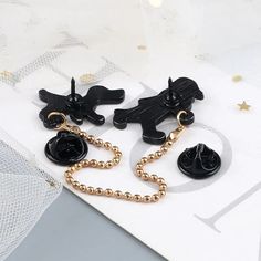 three pairs of black and gold dog earrings on top of a white card with stars