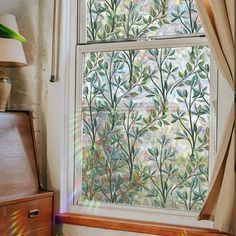 an open window with green leaves on it and a lamp next to the window sill