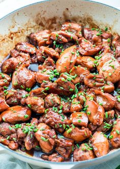 a skillet filled with meat covered in sauce and garnished with green onions