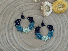 a pair of blue and white beaded hoop earrings on top of a piece of wood