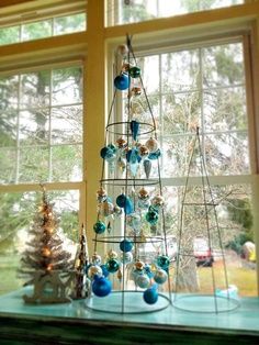 a christmas tree in front of a window with ornaments hanging from it's sides