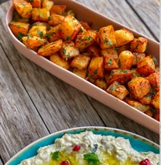 two plates with food on them next to a bowl of hummus and bread in it