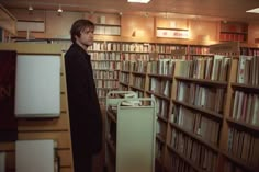 a man standing in front of a bookshelf filled with lots of book shelves