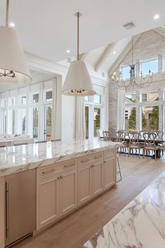 a large kitchen with an island and marble counter tops in front of the dining room table