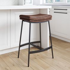 a brown leather seat on a black metal bar stool in front of a white kitchen counter