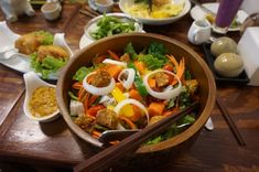 a wooden table topped with bowls filled with food