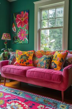 a pink couch sitting in front of a window next to a colorful rug and lamp