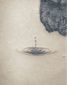 a black and white photo of a water drop on the back of a woman's shoulder