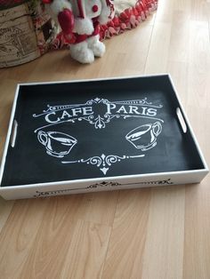 a black and white tray with the words cafe paris written on it next to a stuffed animal