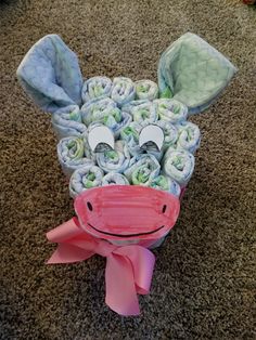 a cow made out of rolled up cloths on the floor with a pink bow