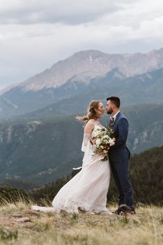 a bride and groom standing on top of a mountain