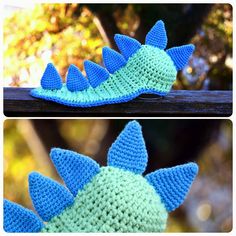 crocheted blue and green dinosaur hat sitting on top of a wooden bench