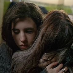 a woman with long hair hugging another woman