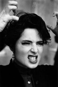 a black and white photo of a woman holding her hair in the air with one hand